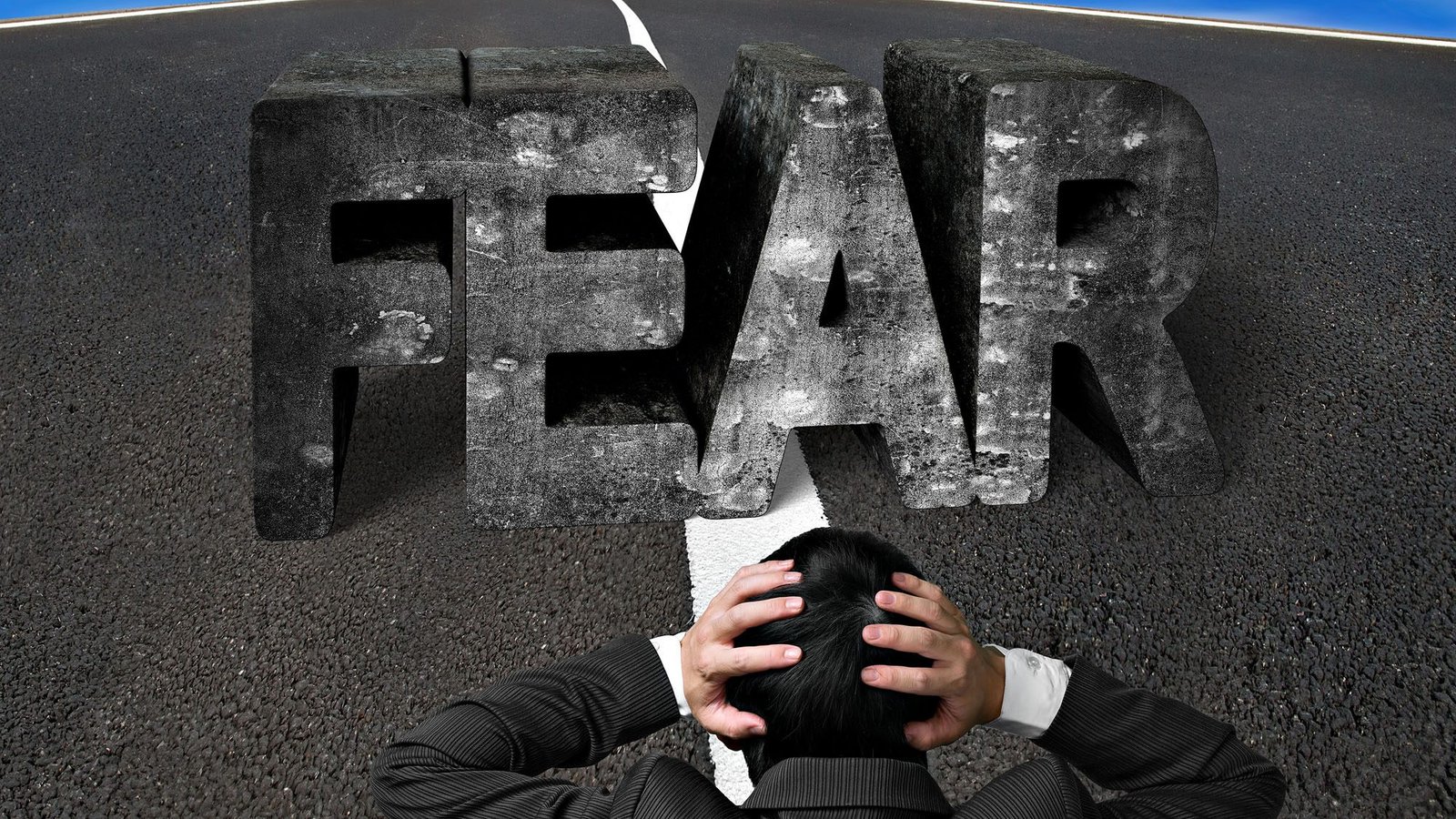 Person in suit facing large 'FEAR' word on road